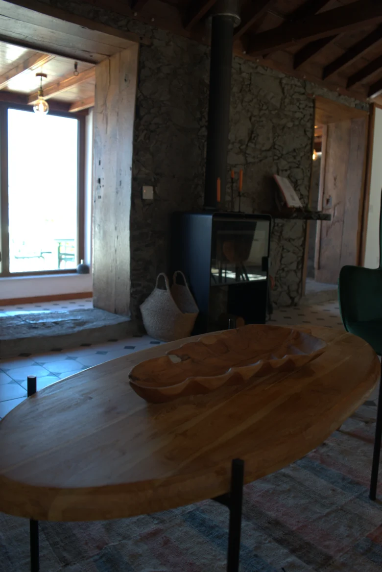 La mesa redonda de madera y la estufa de leña de Casa La Piedra