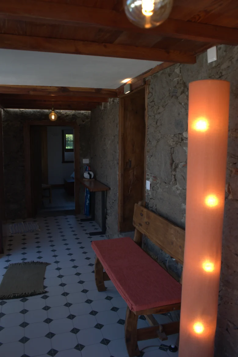 El pasillo de Casa La Piedra con el muro de piedra y el banco rojo