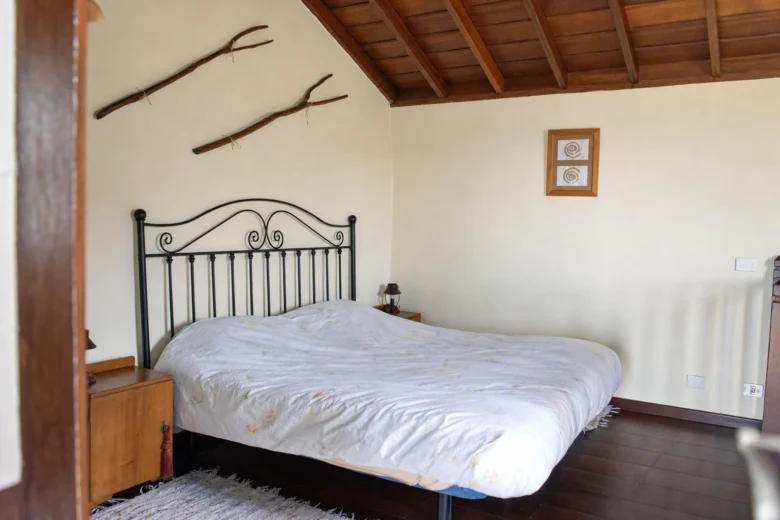 Dormitorio de Cha Miquela Grande con la cama de forja y el suelo de madera
