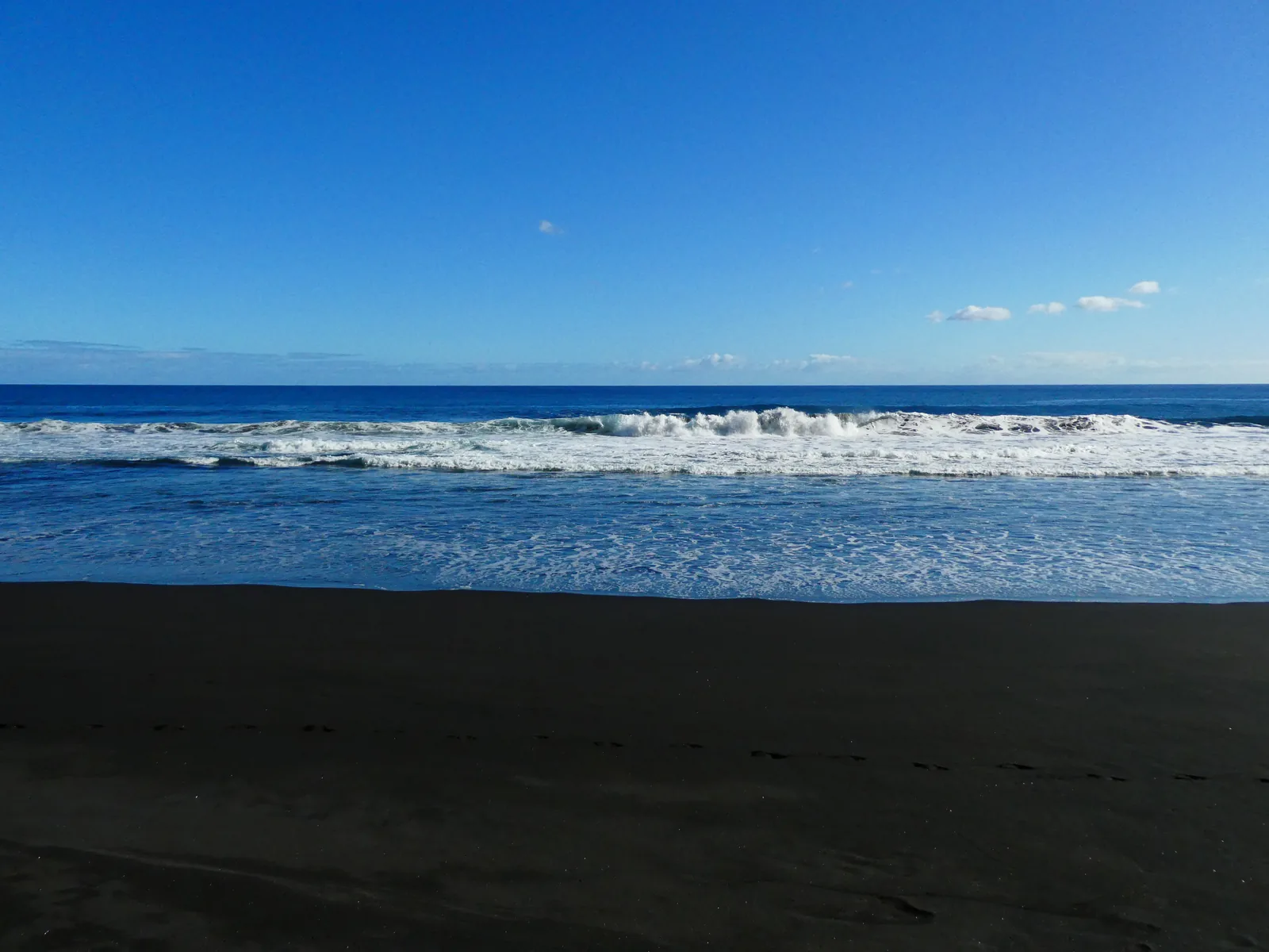 La arena negra de la playa de Nogales con las olas rompiendo, en Puntallana