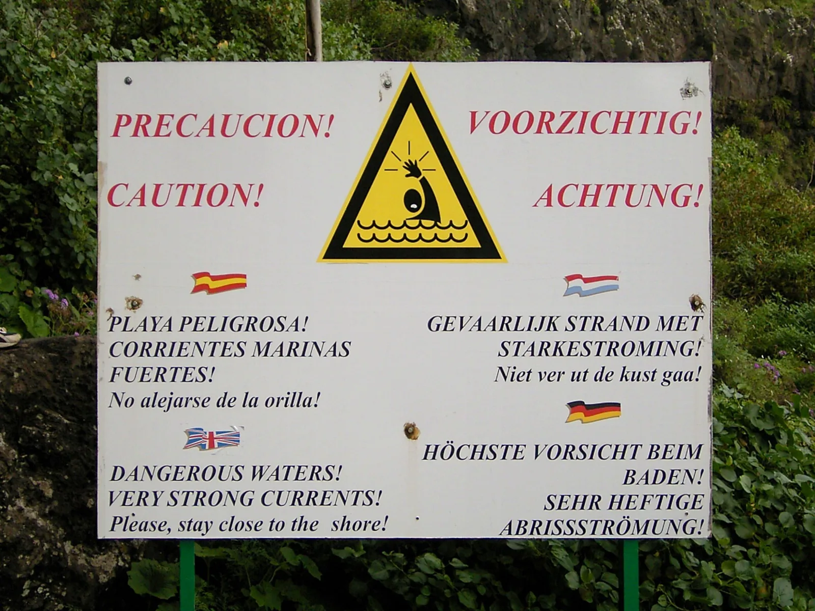 Cartel de aviso de corrientes fuertes en la playa de Nogales, en español, inglés, holandés y alemán